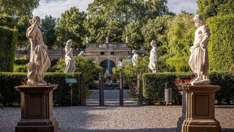 photo d'un jardin en italie avec des arbres, un bâtiment et une enfilade de statues